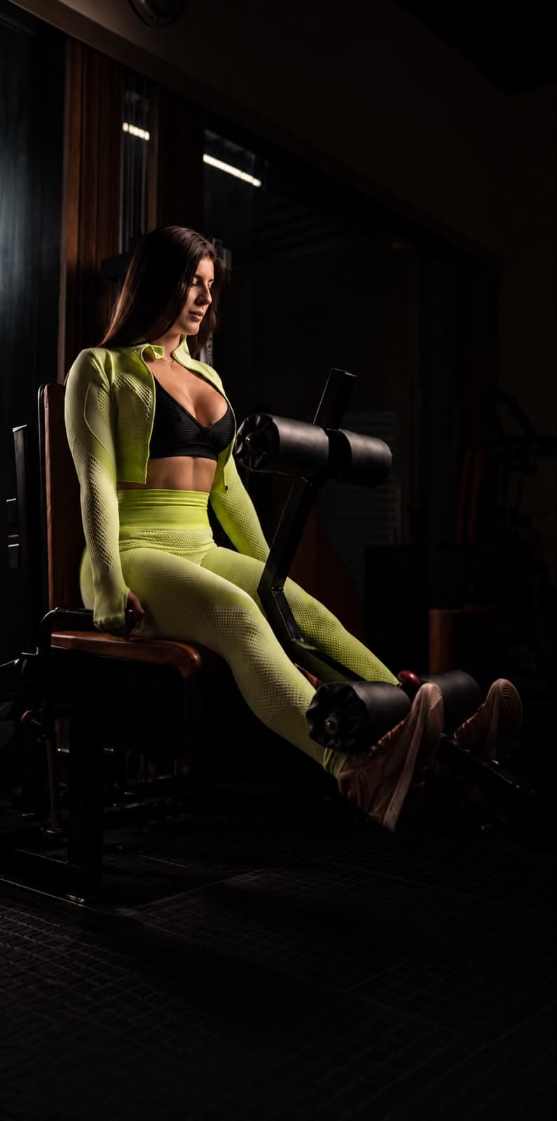 Bárbara Zalla sentada na cadeira extensora, de roupa verde-limão